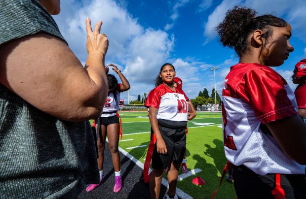 Jennifer Reed, center, a junior quarterback on Lakewood High's girls flag football team who is hearing impaired, looks to Karen Sexton, left, a sign language interpreter, before a game against Jordan High on Wednesday, Oct. 25, 2023, in Lakewood. (Photo by Mark Rightmire, Orange County Register/SCNG)