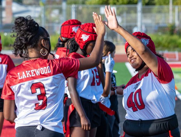 Sabreen Aubrey, left, high-fives Jennifer Reed, right, a junior quarterback on Lakewood High's girls flag football team who is hearing impaired, during a game against Jordan High on Wednesday, Oct. 25, 2023, in Lakewood. (Photo by Mark Rightmire, Orange County Register/SCNG)