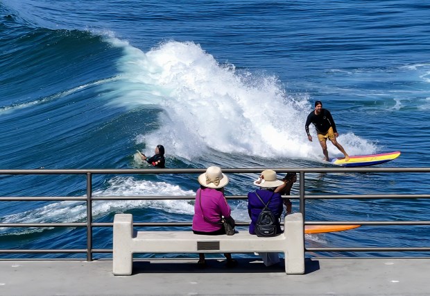 Visitors to the pier watch surfer ride the waves in Huntington Beach, CA, on Tuesday, September 19, 2023. (Photo by Jeff Gritchen, Orange County Register/SCNG)