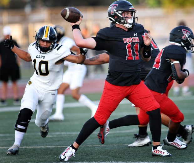 Tustin quarterback Jack Stupin, center, throws the ball up field against Capistrano Valley defenders during Thursday night's varsity football matchup in Tustin August, 18, 2022.(Photo by Greg Andersen, Contributing Photographer)