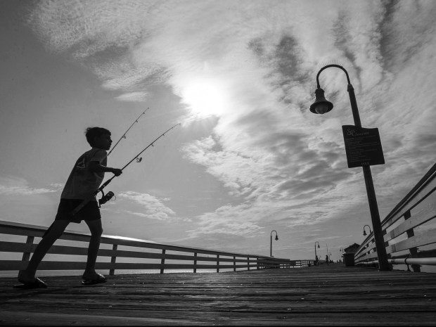 A young fisherman makes his way along the San Clemente Pier in San Clemente in 2019, as clouds begin to roll in to the area.The wooden pier in San Clemente is celebrating its 95th birthday, a centerpiece of the small beach town. (Photo by Mark Rightmire, Orange County Register/SCNG)