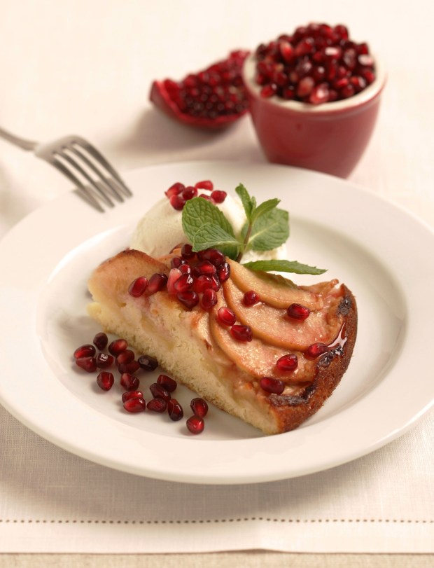 Apple Cake with Pomegranates is topped with overlapping apple slices before baking and then brushed with a pomegranate-jelly glaze, with pomegranate seeds sprinled on top. (Photo by Nick Koon)