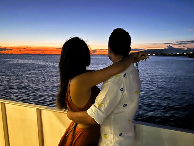 A couple shares a romantic moment on the Waikiki Sunset Cocktail Cruise. (Photo by David Dickstein)