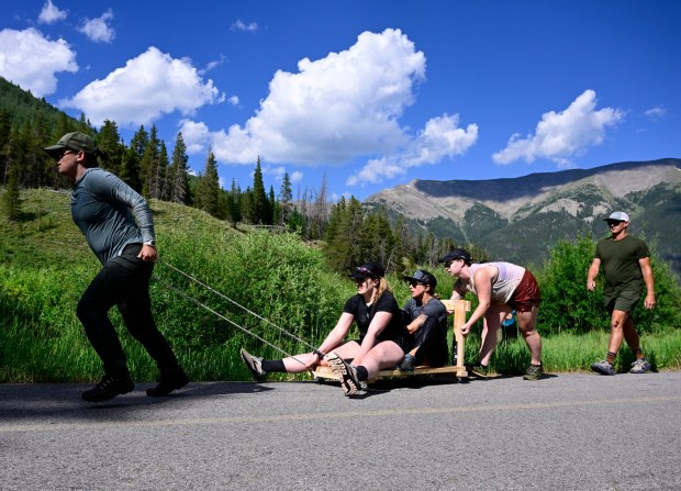 Hericane Rowing team members from left to right, Kristin Hofer, Sierra Myers, Kelsey Pfendler and Jen Hofer pull and push each other up a bike path along Vail Pass on a wooden cart they just built under the watchful eyes of trainer Scott Jones during a grueling sleep deprivation training exercise July 21, 2023. Team Hericane Rowing were training to row across the Pacific Ocean next year in the Great Pacific Race, attempting to beat the women's record of 34 days. (Photo by Andy Cross/The Denver Post)