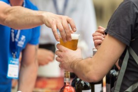 A glass of beer is handed from one person to another.